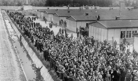 Une foule de détenus en liesse saluant leurs libérateurs devant le fossé marquant la frontière du camp (Crédits photographiques : USHMM)