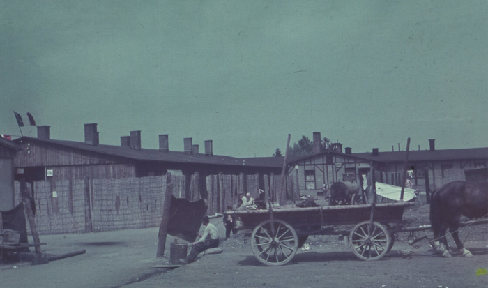 The bordello barrack is located behind a fence on the left of the photo. Next to it on the right, behind the horse and cart, the disinfection barrack is somewhat further away.