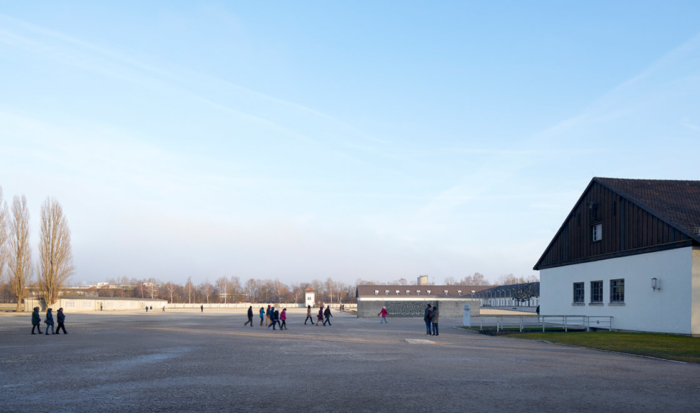 After entering the Memorial Site grounds through the Jourhaus gate, visitors stand on a spacious area covered with gravel. This is the former roll call area; it directly adjoins the former maintenance building, located to the right.