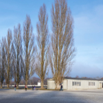 Steht man nun mit dem Rücken zum ehemaligen Wirtschaftsgebäude, befindet sich auf der rechten Seite der Pappelallee eine nachgebaute Baracke, die den früheren Standort des Krankenreviers markiert.