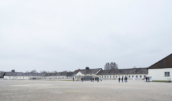 Das ehemalige Wirtschafts·gebäude. In der Mitte: Das Internationale Mahn·mal. Das Foto ist von 2017. (KZ-Gedenk·stätte Dachau)