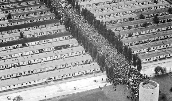 Toma aérea que muestra el antiguo terreno del campo de prisioneros desde arriba y desde la Capilla de la Agonía de Cristo. La antigua calle del campo está llena de gente (Derechos de imagen: Editorial Luftbildverlag Bertram).