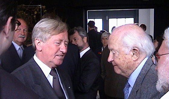 El ministro de Cultura Hans Zehetmair (izq.) con el sobreviviente Hans Taschner (dcha.) conversando durante la inauguración de la exposición principal del Memorial del Campo de Concentración de Dachau, 2 de mayo de 2003 (Derechos de imagen: Memorial del Campo de Concentración de Dachau).