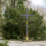 Umringt von Bäumen und Büschen wurde auf einem Kiesweg ein großes Kreuz aufgestellt.
