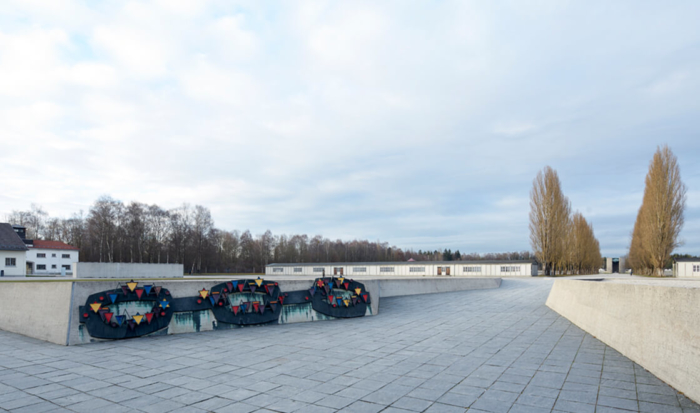 Gegenüber von der Skulptur ist ein Relief an einer Mauer angebracht, das in Form einer Kette die Solidarität der Häftlinge symbolisiert. Winkel in verschiedenen Farben und Größen sind auf diesem Relief angebracht.