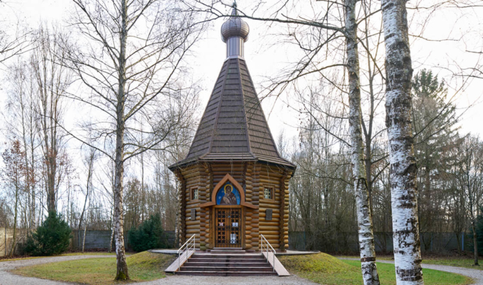 Located on the way to the memorial area of the crematorium on the left-hand side, after crossing the bridge over the Würm canal, is the Russian Orthodox chapel. An octagonal timber structure built in a simple cabin style, it stands in the middle of a quiet, tree-lined lawn. The steep tent shape recalls traditional Russian architecture, while a Russian cross is positioned on top of the shingle-clad roof hood. An icon of the Mother of God with a child is mounted over the entrance.