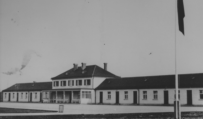 The maintenance building was a long, single storied structure with a two-storied main section between the two wings. An open porch-like annex is on the ground level; roofed over, benches are arranged to face roll call area.