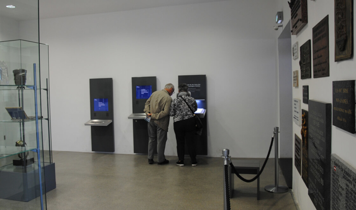 Entrando nella sala commemorativa troviamo, sul lato destro, tre terminali che danno la possibilità di ricercare i caduti nel campo di concentramento di Dachau sulla base dei nomi nel cosiddetto ”libro commemorativo”.