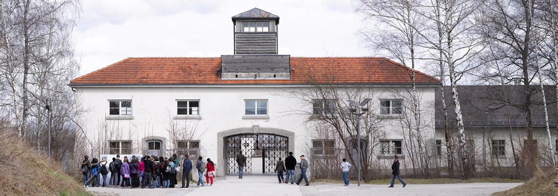 Foto di un gruppo di visitatori davanti all'ex Jourhaus, ex ingresso del campo dei detenuti