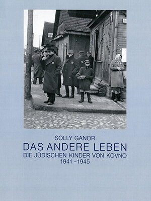 Das Cover des Ausstellungskatalogs „Solly Ganor – Das andere Leben” zeigt eine Fotografie von einigen jüdischen Männern und Frauen, die an einer Straßenecke stehen. In der Bildmitte ist ein Junge mit einer großen Schüssel zu sehen.