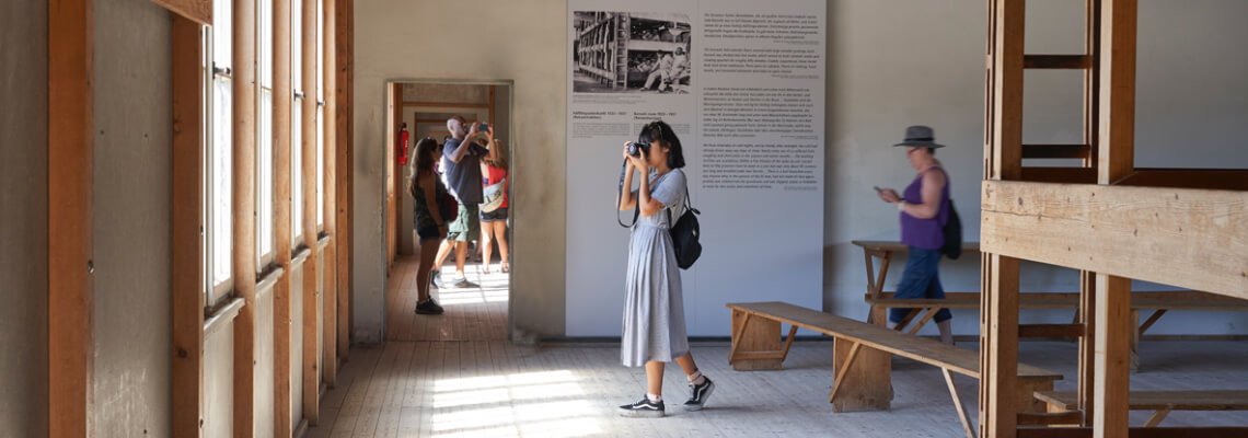 Blick auf eine Ausstellungstafel in der Modellbaracke mit den nachgebauten Holzbettgestellen