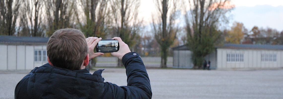 Junger Besucher, der mit seinem Smartphone die ehemalige Lagerstraße fotografiert.