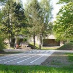 Zwei Besucher stehen vor dem Mahnmal auf dem ehemaligen “SS-Schießplatz Hebertshausen”, rechts von ihnen ist der Kugelfang aus Beton zu sehen.