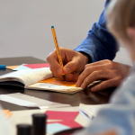 Schülerinnen und Schüler beim schriftlichen Verarbeiten ihrer Eindrücke nach dem Besuch der KZ-Gedenkstätte Dachau