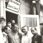 Befreite Häftline vor einer Baracke mit der Aufschrift des Sowjetischen Häftlingskomitees vermutlich im Mai 1945