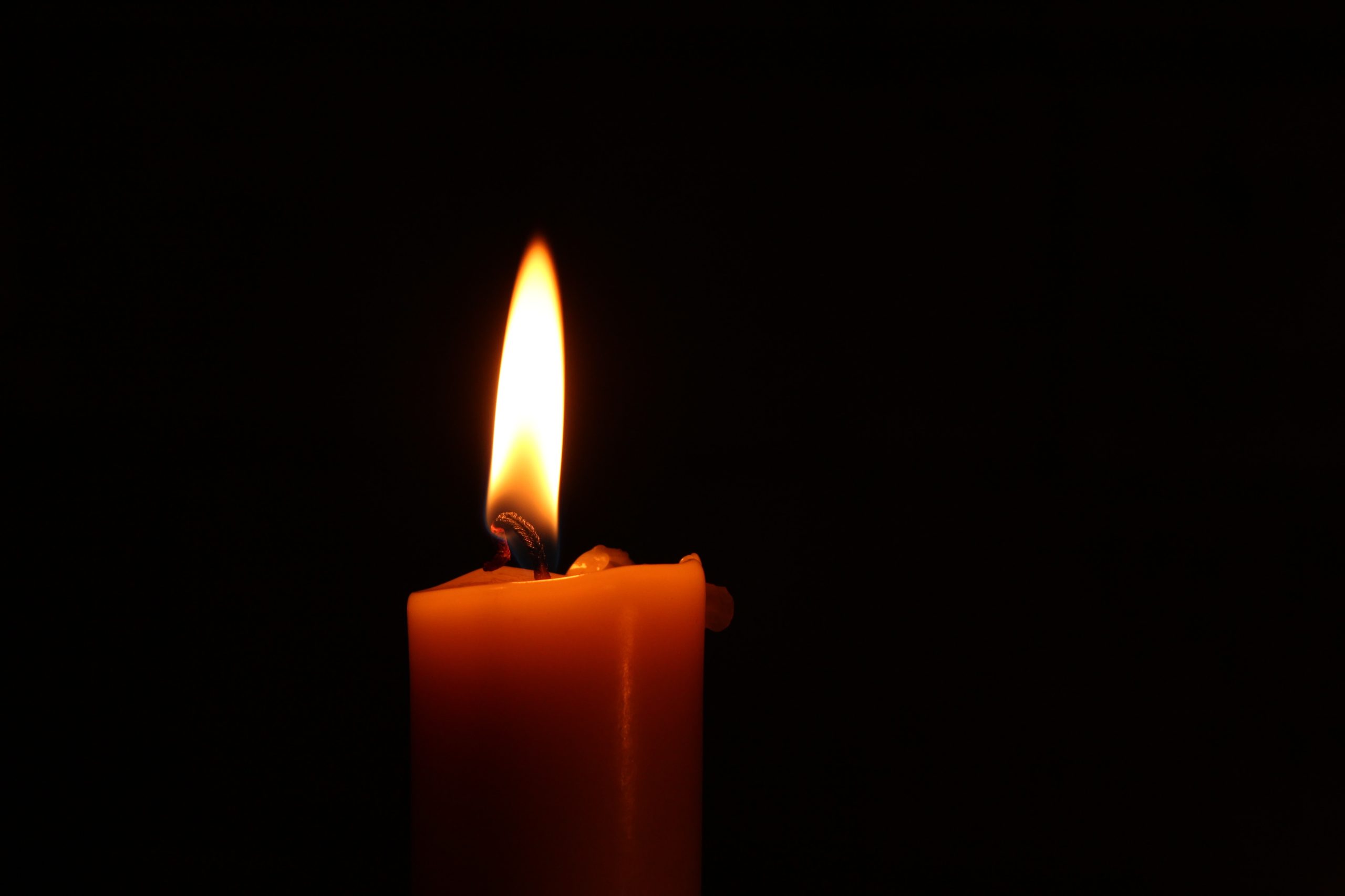 Brennende Kerze auf dunklen Hintergrund