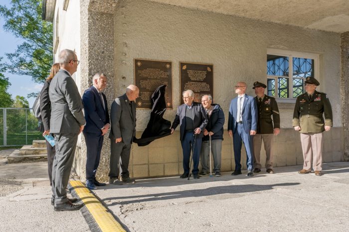Zwei Personen enthüllen die Gedenktafel, mehrere stehen daneben