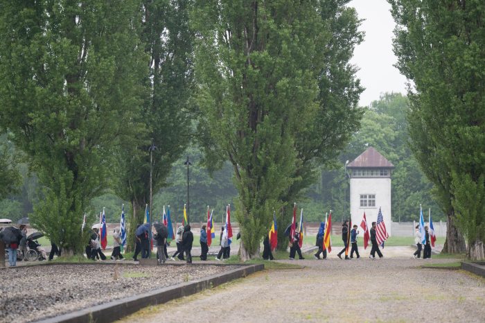 Seitlicher Blick auf den Zug über die ehemalige Lagerstraße, Teilnehmende halten verschiedene Nationalflaggen