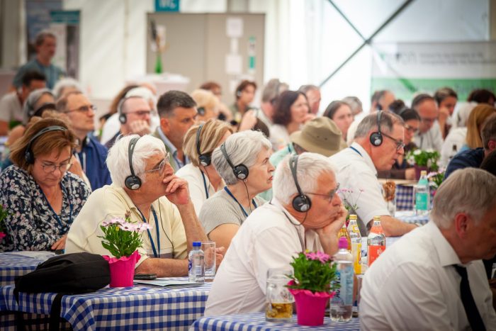 Die Teilnehmenden verfolgen die in drei Sprachen übersetzte Podiumsdiskussion
