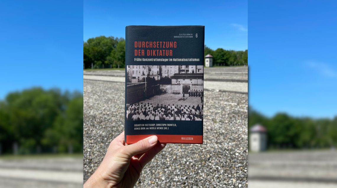 Die Abbildung zeigt eine Hand, die das Cover des Sammelbandes in die Luft hält.